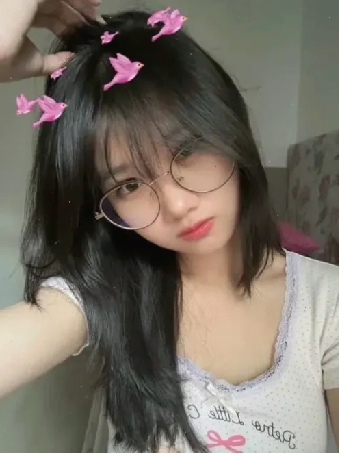 Cô gái đeo kính mặc áo tím đứng giữa lối cây xanh
