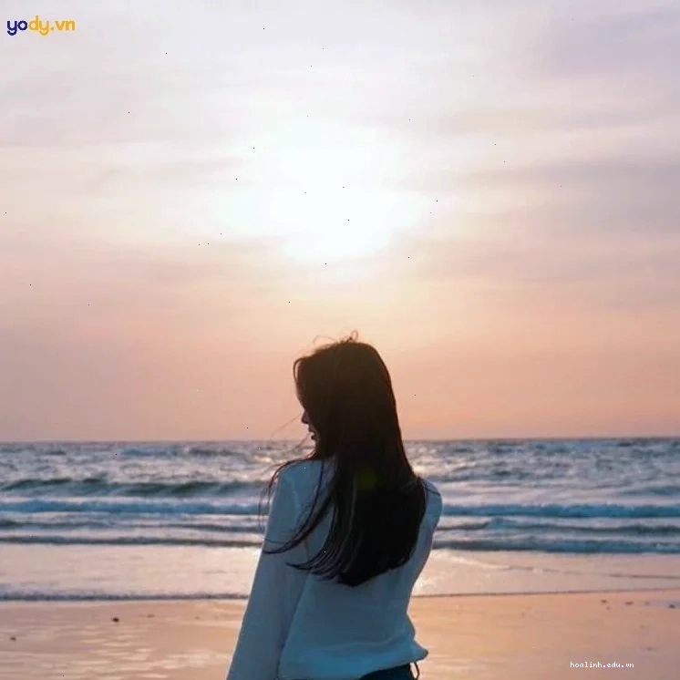 Một cô gái đứng nhìn về hướng biển với phía sau lưng cô gái