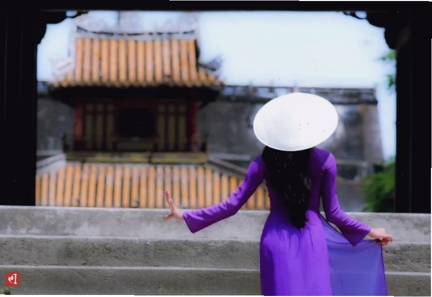 Một hình ảnh cô gái huế mặc áo dài tím đứng bên dòng sông Hương
